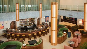 Een moderne bar met een gebogen toonbank, verschillende barkrukken, en een zithoek met banken en tafels.