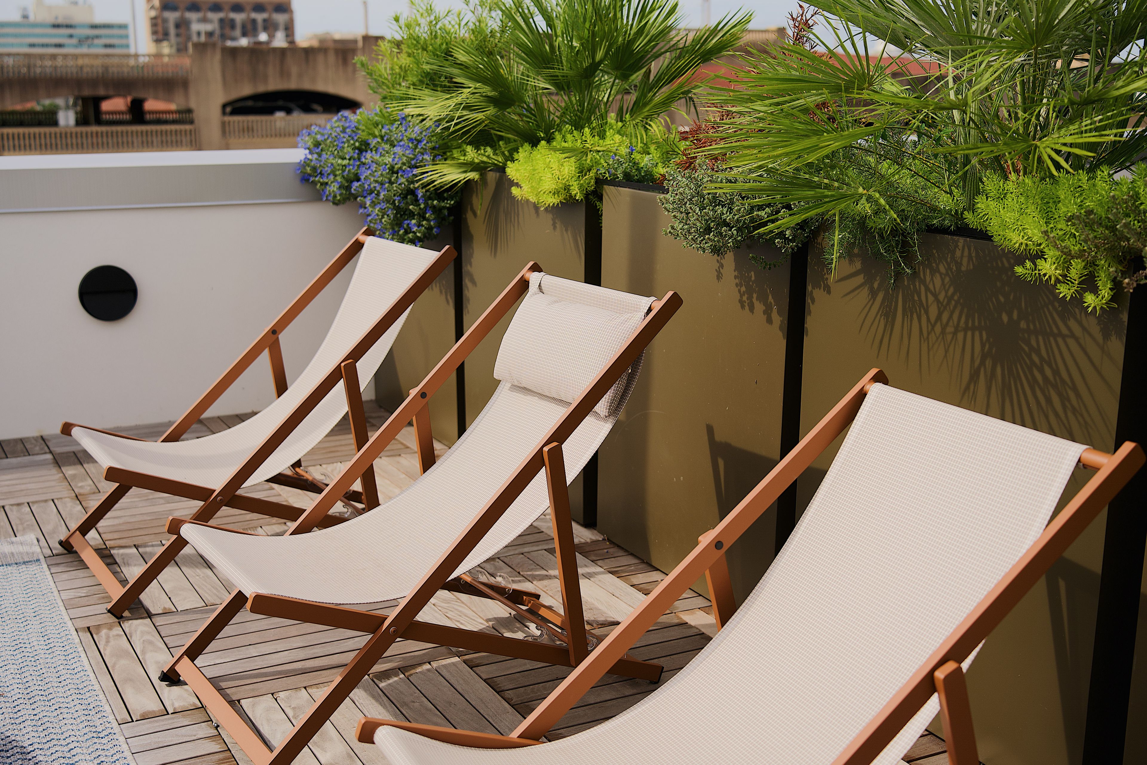 Three wooden lounge chairs with mesh seats on a wooden deck.