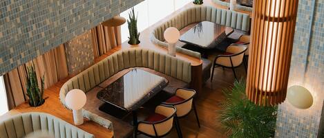 A modern dining area with cushioned seating, a glass-top table, and ambient lighting.