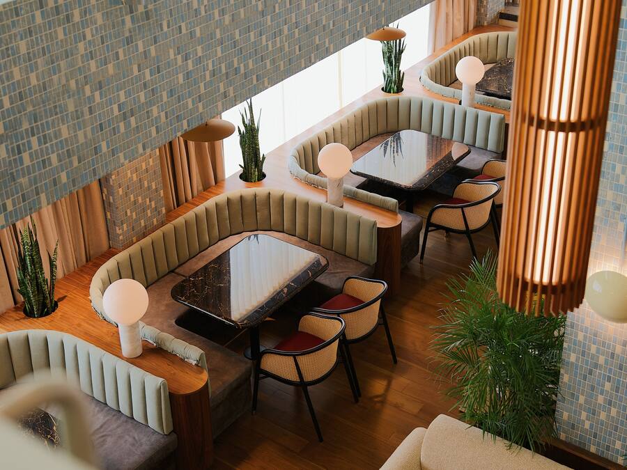 A modern dining area with cushioned seating, a glass-top table, and ambient lighting.