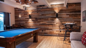 A pool table in a room with wooden walls and a sofa. - Bear Lodge (Tahoe City)