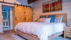 A bedroom with a wooden bed, a sliding barn door closet, a painting, and a nightstand. - Bear Lodge (Tahoe City)