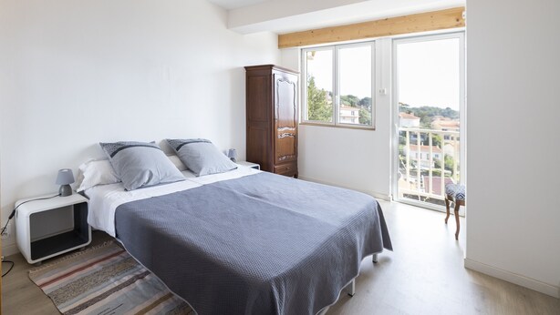 A bedroom with a bed, nightstand, wardrobe, and a view through a large window. - La Belle Escapade - Climatisée, aperçu mer (Port-Vendres)