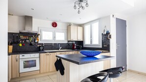 A modern kitchen with a central island, wooden cabinets, and a black countertop. - La Belle Escapade - Climatisée, aperçu mer (Port-Vendres)