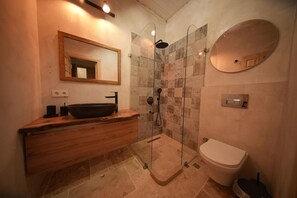 Une salle de bain moderne avec un meuble-lavabo en bois, un lavabo sur pied noir, une douche à parois de verre et un miroir rond.
