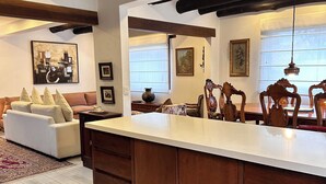 A spacious living area with a large wooden dining table, a sofa, and a kitchen with a central island. - La marquesa casa hotel (Villa de Leyva)