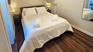 Une chambre à coucher avec un lit, un ventilateur de plafond, une table de chevet, une lampe et un miroir.