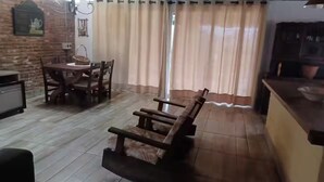 A dining area with a wooden bench, a table, and chairs. There is a kitchen area with a counter and cabinets. - Beach House in Cassino RS (Rio Grande)