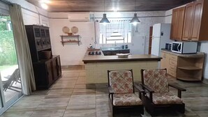 A spacious kitchen with a central island, wooden cabinets, and a dining area with two chairs. - Beach House in Cassino RS (Rio Grande)