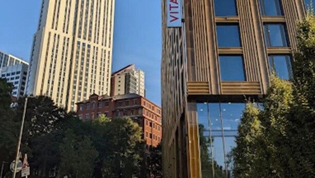 A modern building with a 'VITA' sign, surrounded by other high-rise buildings and trees. - Student Only Vita St. Albans (Leeds)