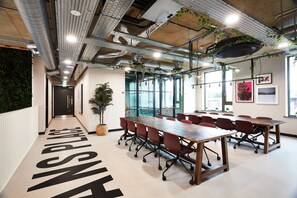 A modern conference room with a long table, multiple chairs, and a potted plant. - Student Only Vita St. Albans (Leeds)