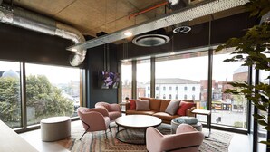 A modern interior with large windows, a round coffee table, and a sofa set. - Student Only Vita St. Albans (Leeds)