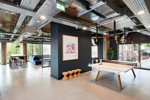 A modern indoor space with a ping pong table, seating area, and artwork on the wall. - Student Only Vita St. Albans (Leeds)