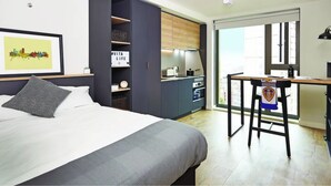 A modern bedroom with a bed, a desk, and a kitchenette. - Student Only Vita St. Albans (Leeds)