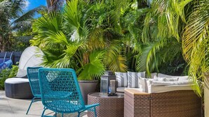 Eine Terrasse mit Korbmöbeln, einem runden Tisch und einer integrierten Bank.
