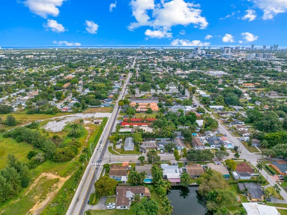An aerial view of a residential area with houses, roads, and a large body of water.