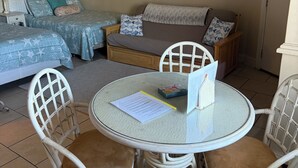 Ein gemütliches Zimmer mit zwei Betten, einer Couch und einem runden Tisch mit Stühlen. An der Wand hängt ein Bild und ein Schild mit der Aufschrift 'RELAX'.
