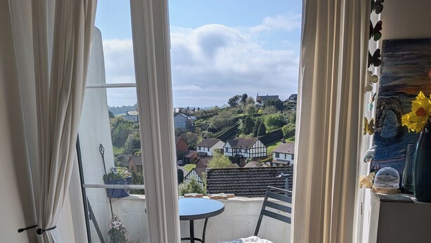 Une pièce avec vue sur un village, une petite table, une chaise et un tapis aux couleurs vives.