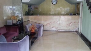 A reception area with a marble counter, a clock, and a seating area with a glass table and chairs. - Dishuiwan Fashion Hotel (Shanghai)