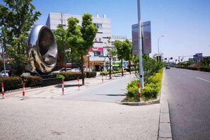Une rue bordée d’une grande sculpture métallique, d’un trottoir et d’une chaussée.