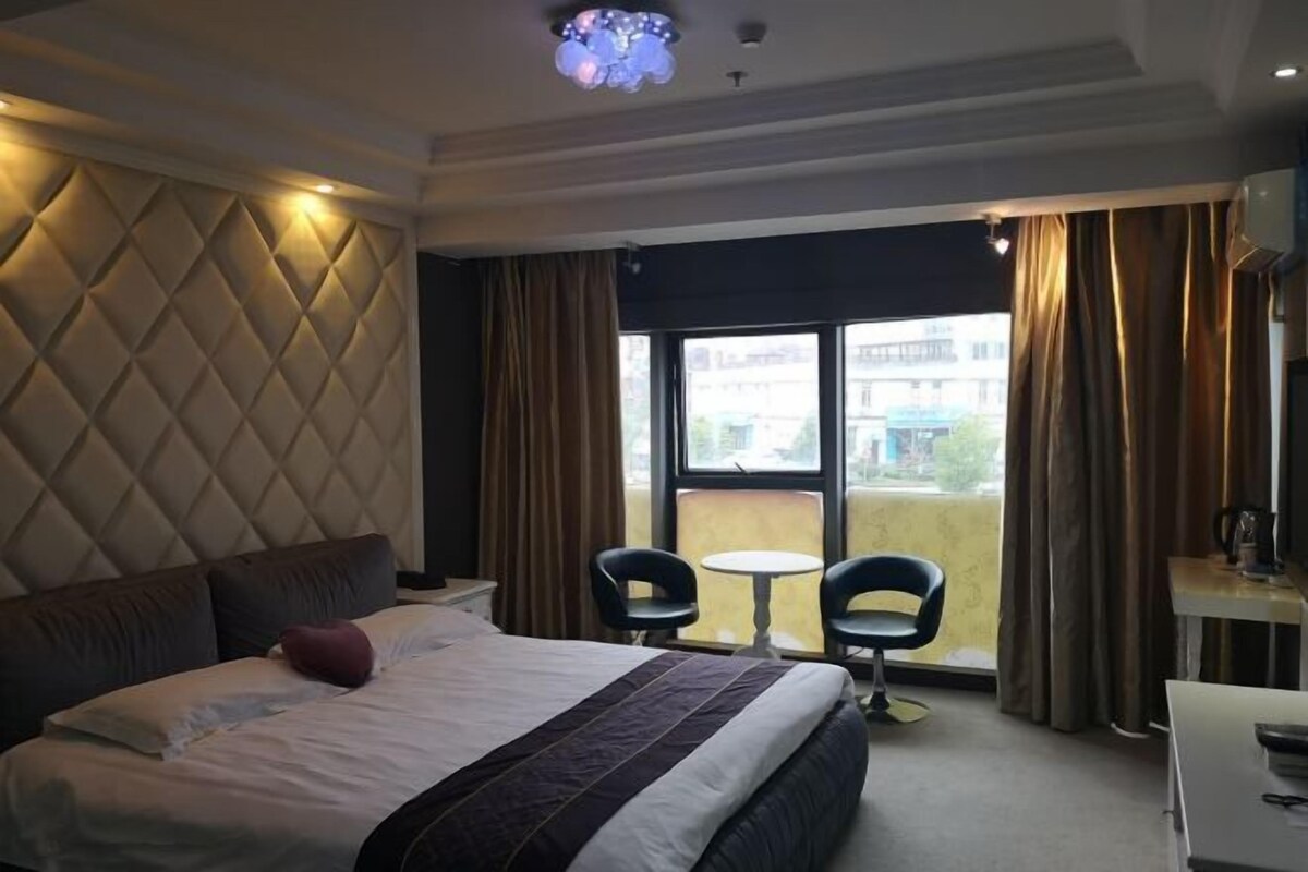 Une chambre d’hôtel avec un grand lit, deux chaises, une petite table et une vue sur l’extérieur.