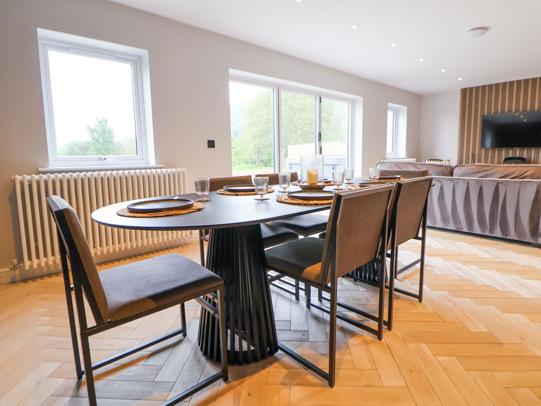 A dining area with a round table set for six, surrounded by chairs.