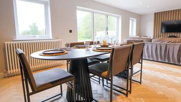 A dining area with a round table set for six, surrounded by chairs.