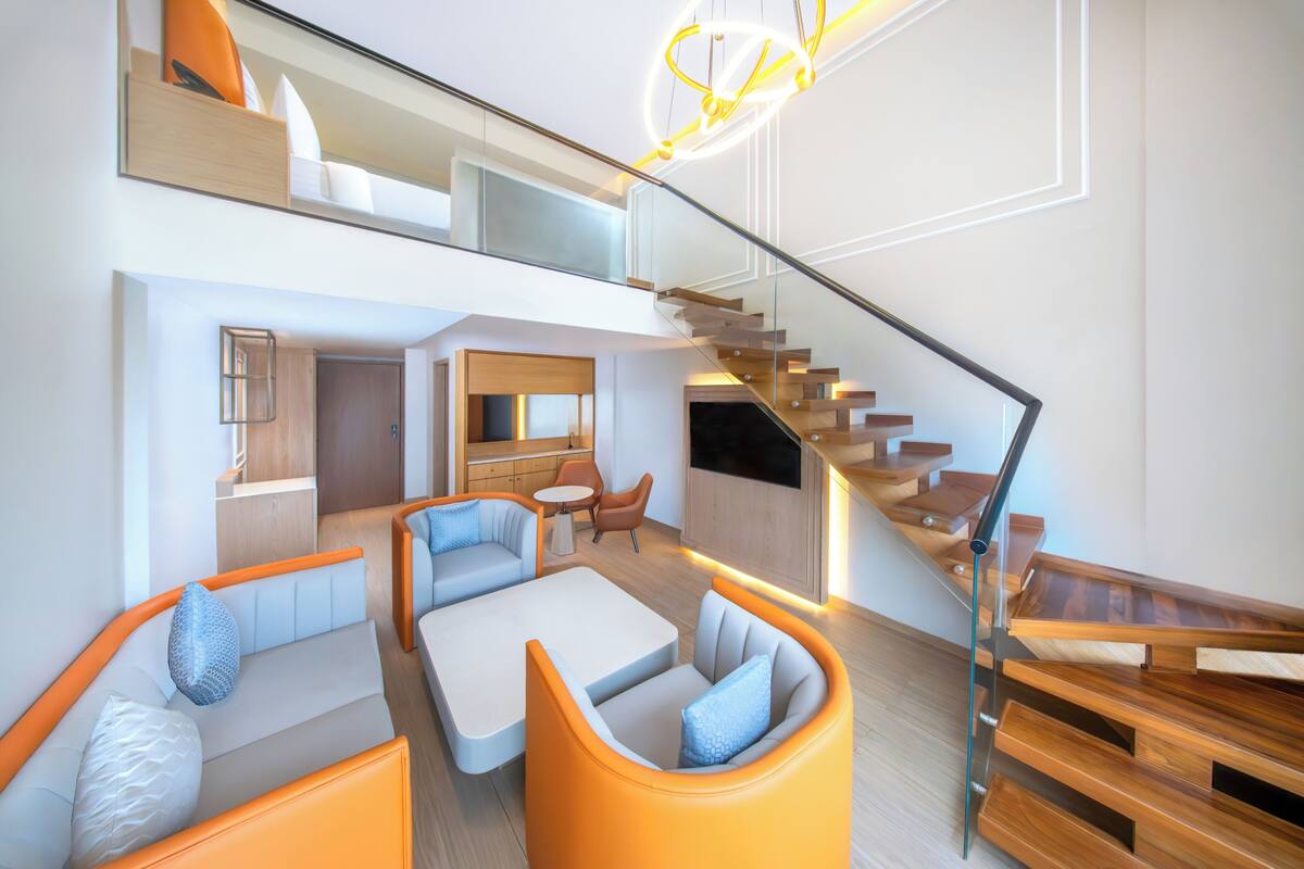 A modern interior with a staircase, seating area, and kitchen.