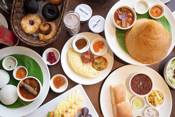 A variety of Indian dishes including a dosa, idli, and a basket of pastries. - Hilton Garden Inn Bengaluru Whitefield (Bengaluru)