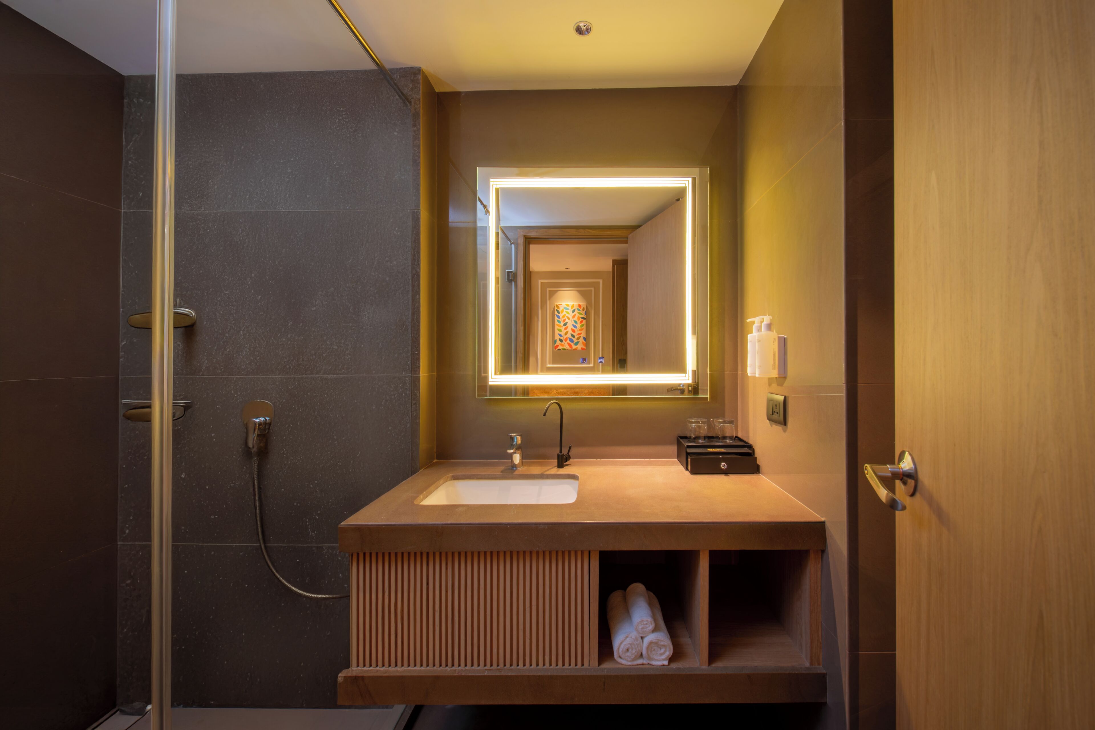 A modern bathroom with a glass shower enclosure, a sink with a mirror, and a towel rack.