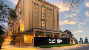 Een groot gebouw met een bord voor Hilton Garden Inn, met een moderne gevel, grote ramen en een overdekte ingang.