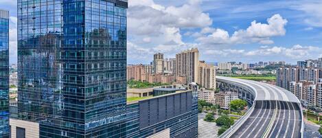 A Hilton Garden Inn hotel with a modern glass facade, surrounded by a cityscape and a curved highway.