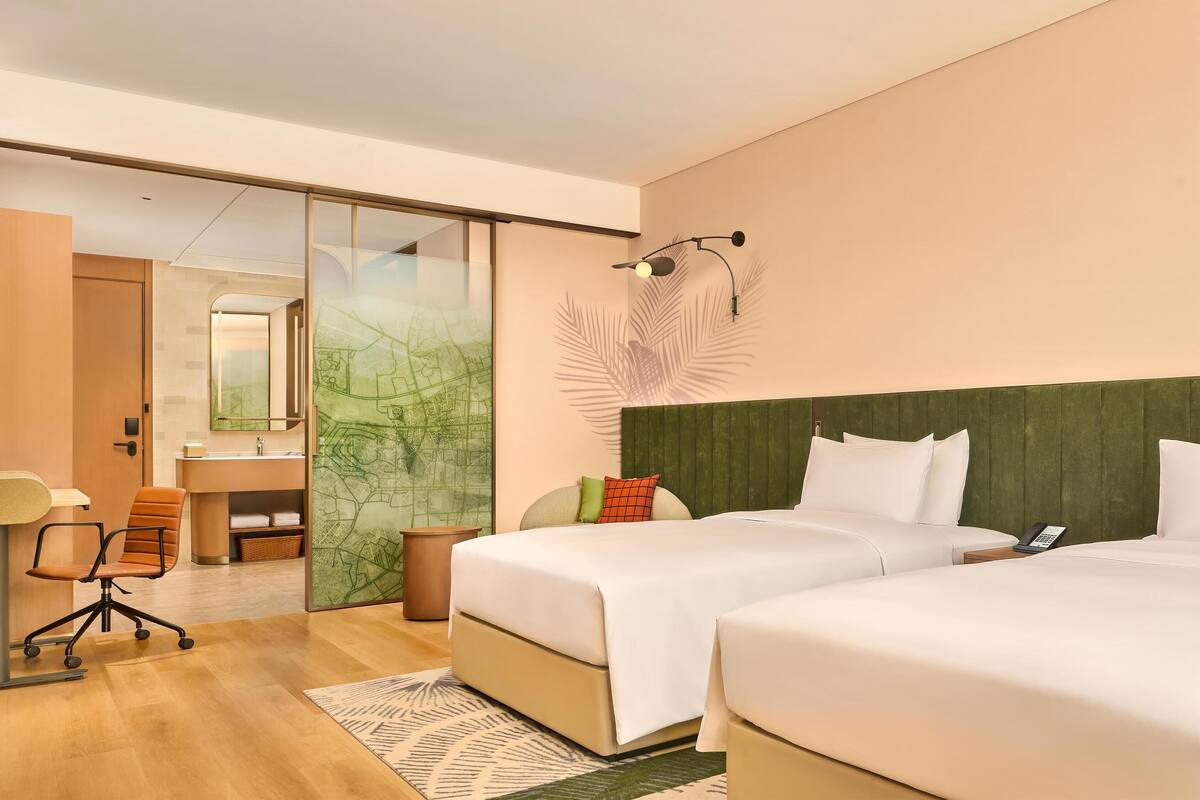 Een hotelkamer met twee bedden, een bureau, een stoel, een badkamer en een kaart aan de muur.