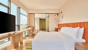 A modern hotel room with a large bed, a desk, a TV, and a balcony with a view. - Hilton Garden Inn Zhongshan South (Zhongshan)