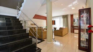 Ein modernes Interieur mit einer Treppe, einem Wohnbereich mit Sofas, einer Glastausch und einem Essbereich.