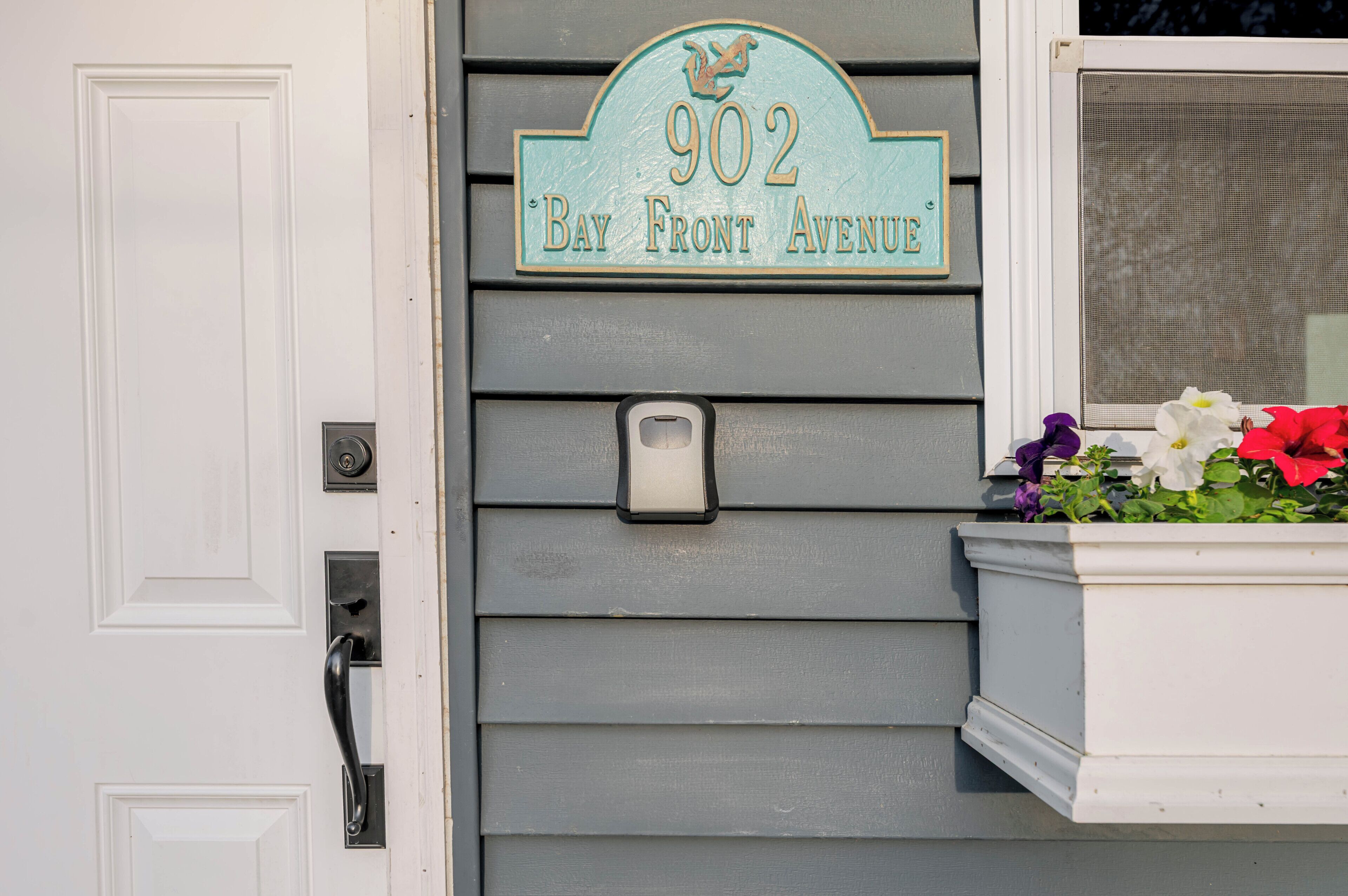 A house number sign on a gray house exterior.
