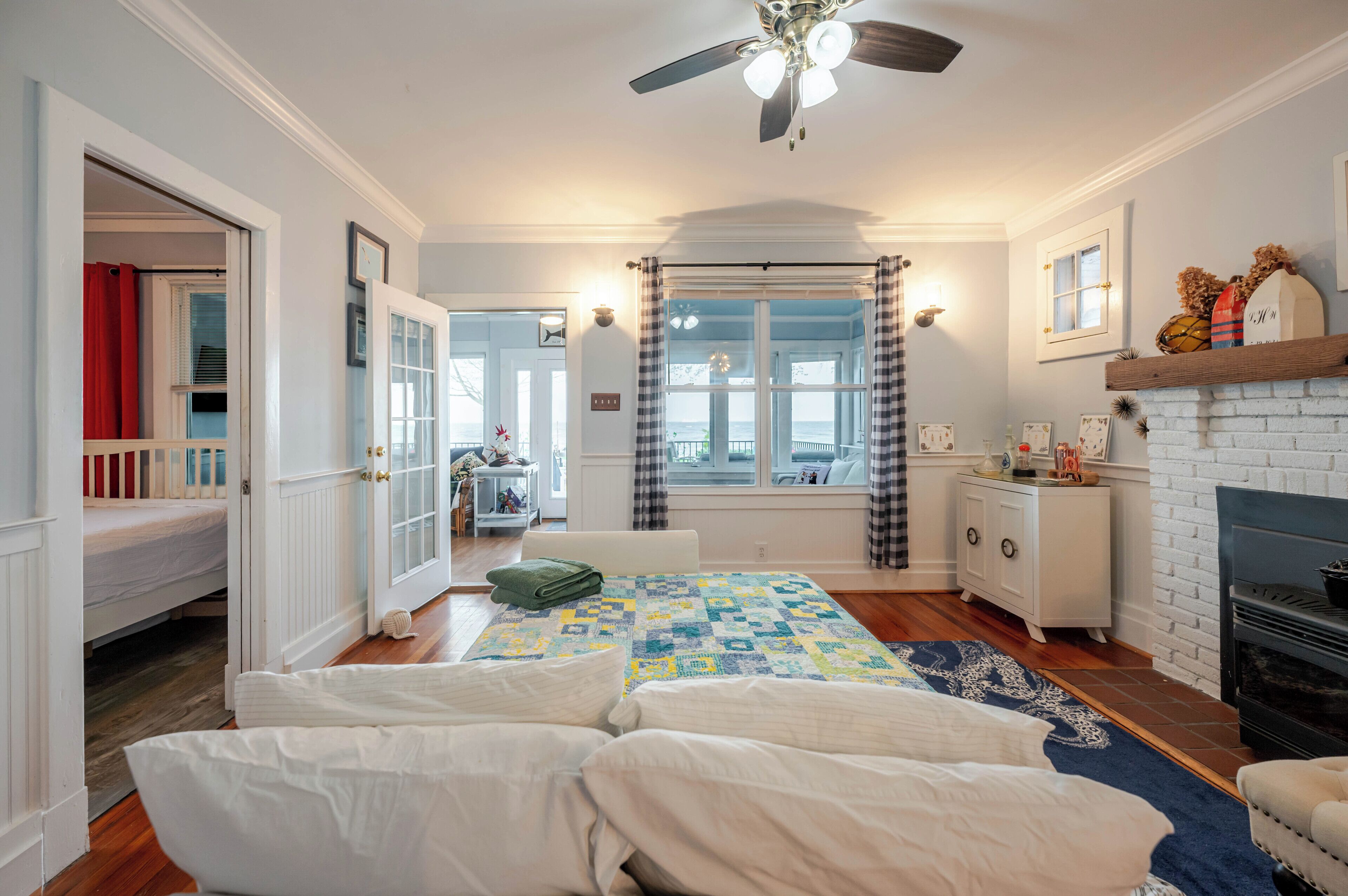 A bedroom with a bed, a dresser, a window, and a fireplace.