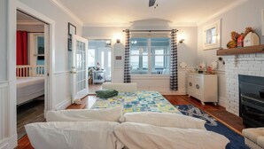 A bedroom with a bed, a dresser, a window, and a fireplace.