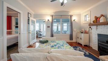 A bedroom with a bed, a dresser, a window, and a fireplace.
