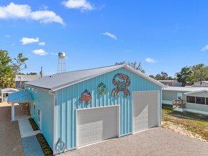 A light blue building with a garage door, a water tank on a tower, and a mural of colorful crab decorations. - Twisted Fiddler - sleeps 14 with private  boat slip (Steinhatchee)
