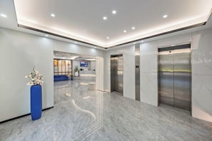 A modern lobby with marble flooring, a reception desk, and two elevators. - Super 8 Hotel Premier (Xiamen Railway Station) (Xiamen)