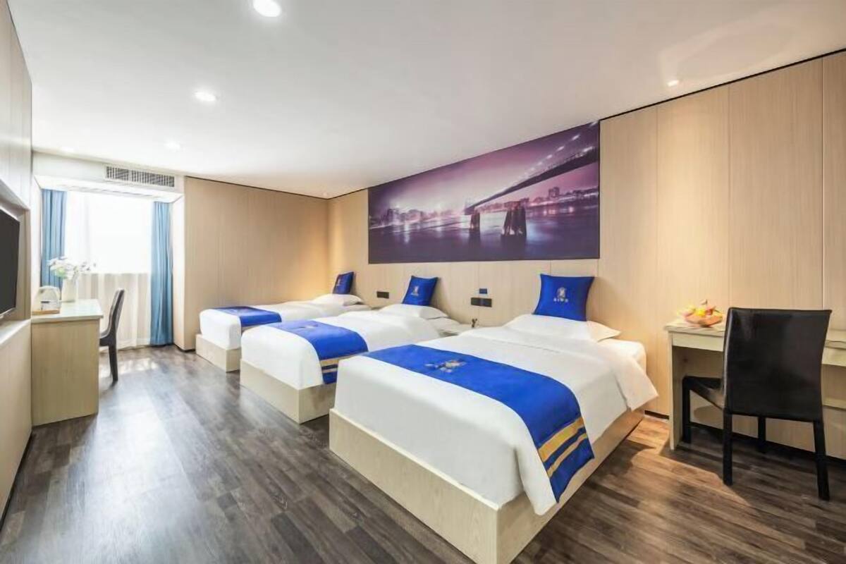 A hotel room with two beds, a desk, a chair, and a large window.