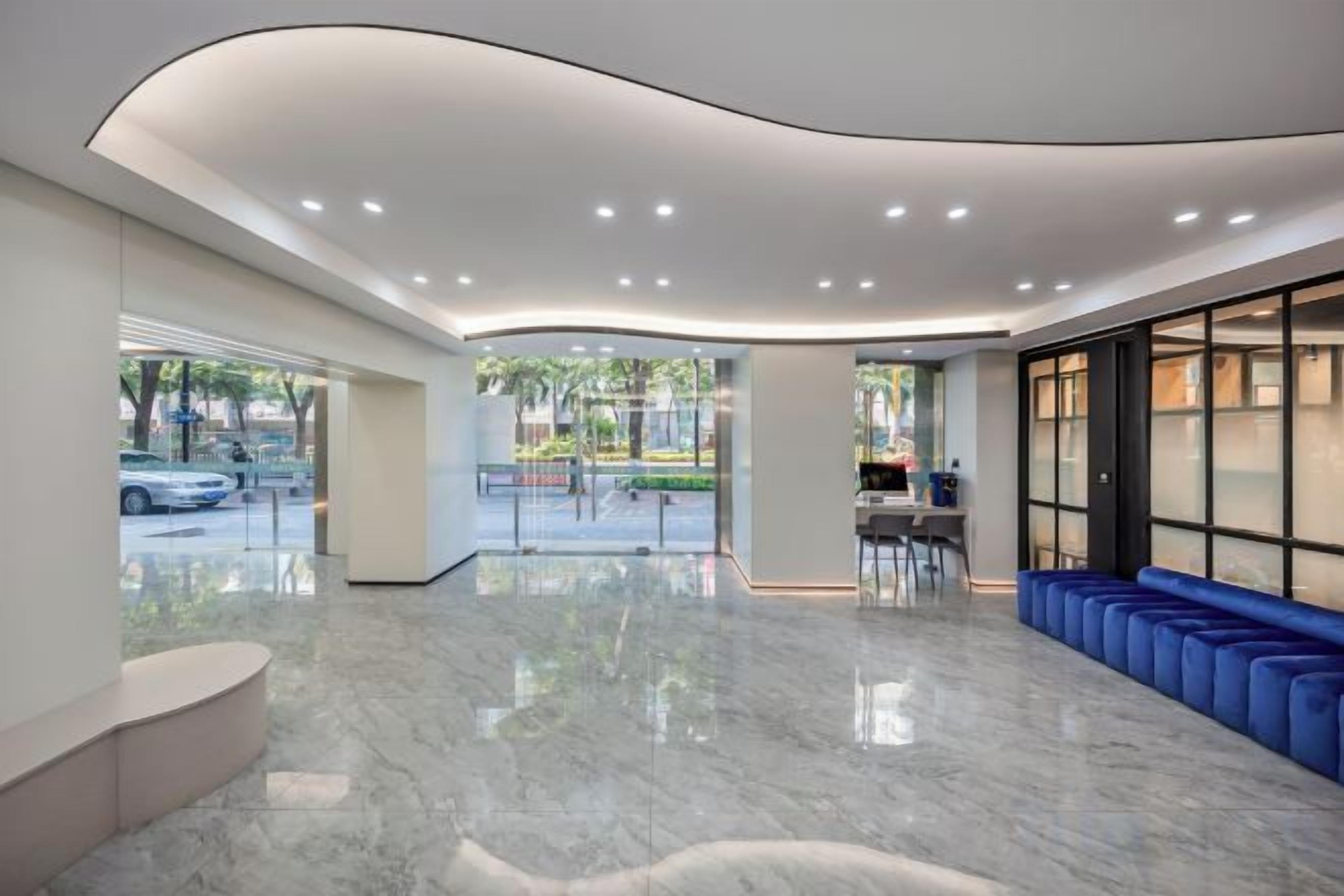 A modern lobby with a curved ceiling, a seating area with blue chairs, and a view of the outdoors.