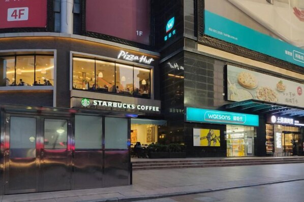 En bygning med butiksvinduer, herunder Starbucks Coffee, Pizza Hut og Watsons.