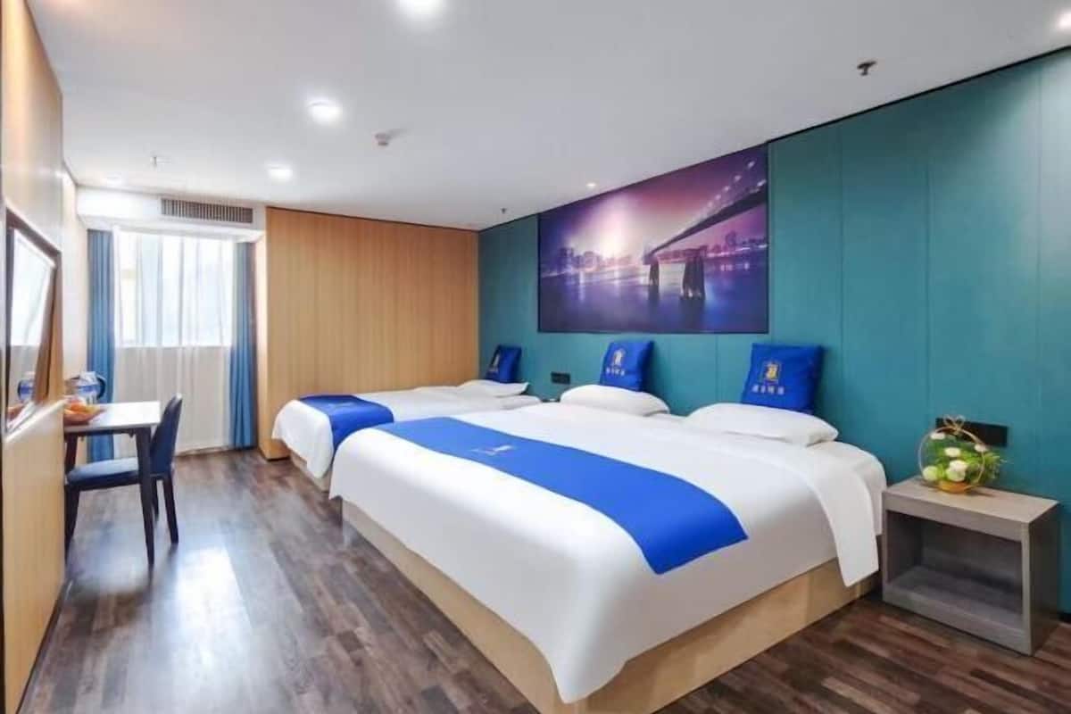 A hotel room with two beds, a desk, and a window with curtains.