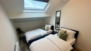 Un dormitorio con dos camas, un tragaluz, un radiador y un espejo.