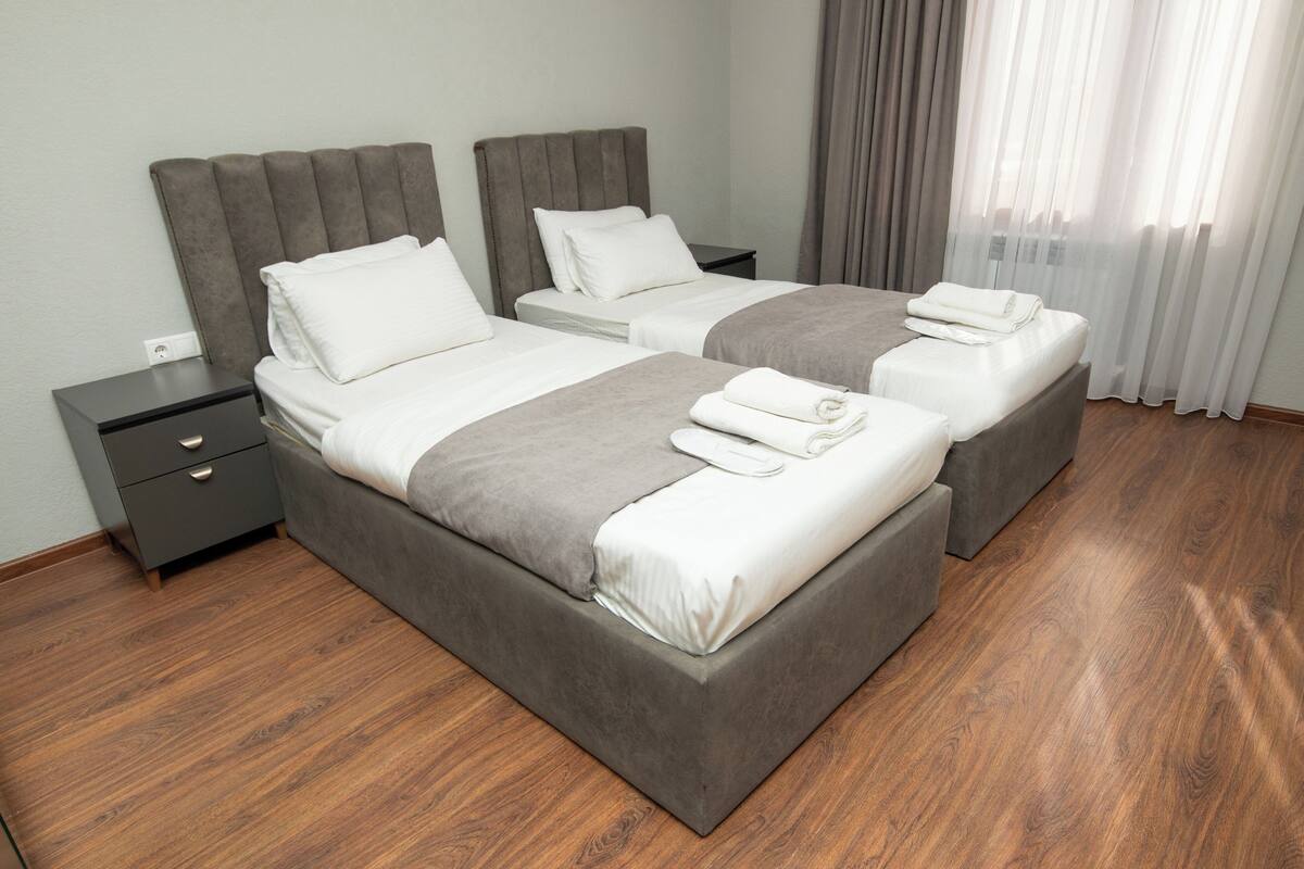 Habitación doble con dos camas, una mesita de noche y piso de madera.