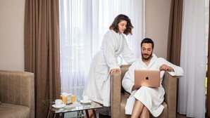 A room with a glass table, a sofa, and two people in robes.