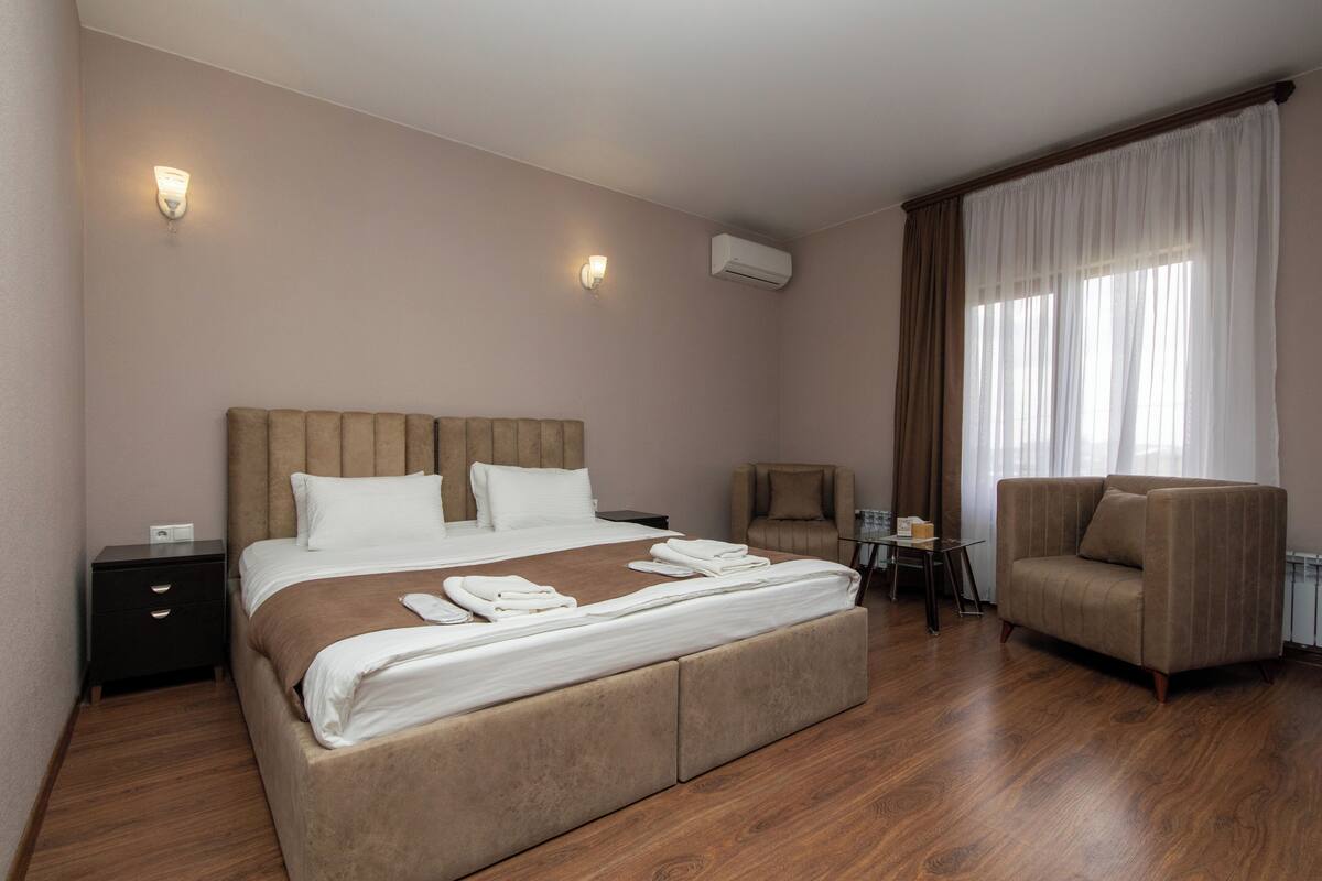 Una habitación de hotel con una cama grande, dos mesitas de noche, una silla y un sofá.