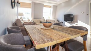 A modern dining area with a wooden table, grey upholstered chairs, and a large bowl centerpiece. - Priory (St Austell)